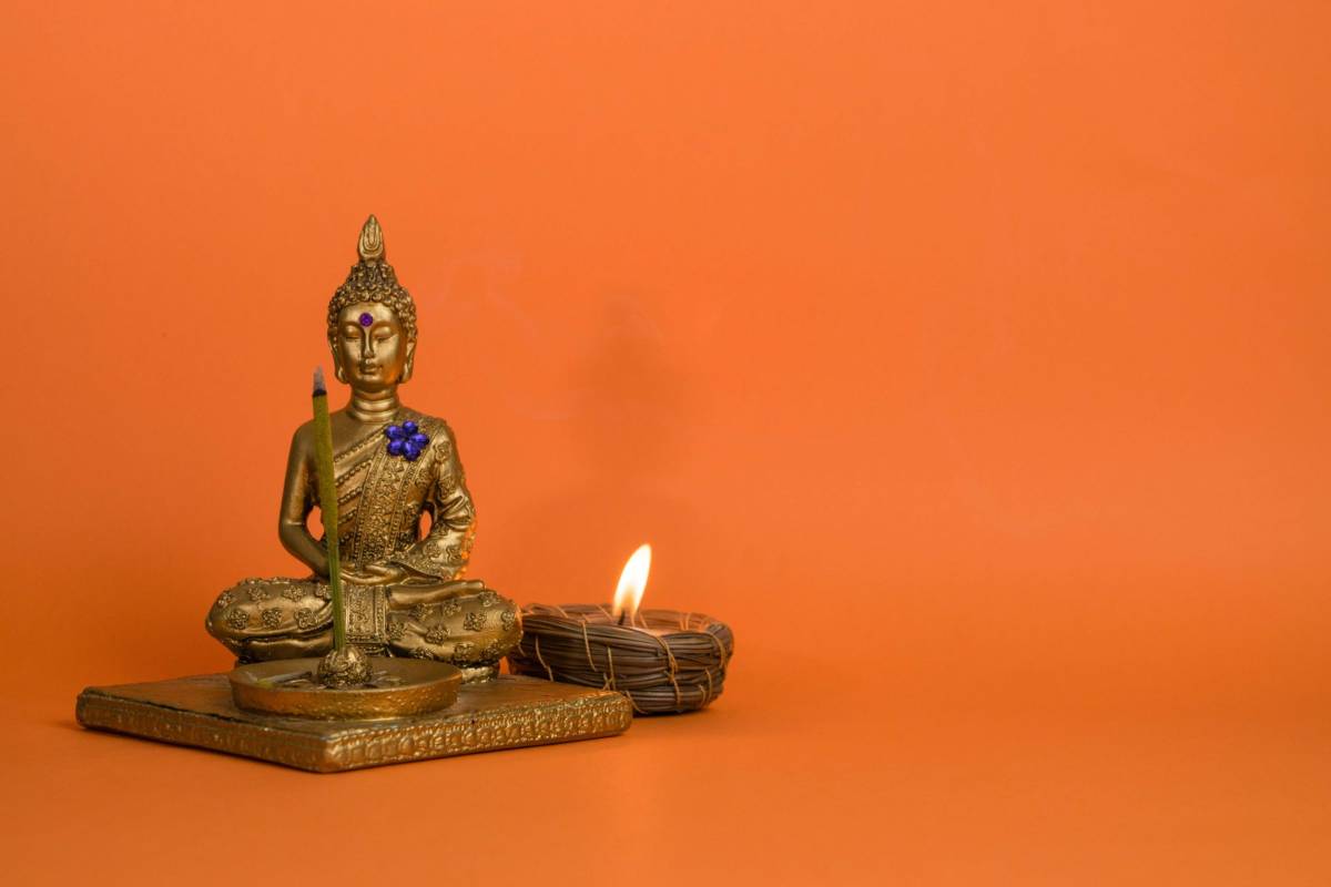 a buddha sitting next to a candle